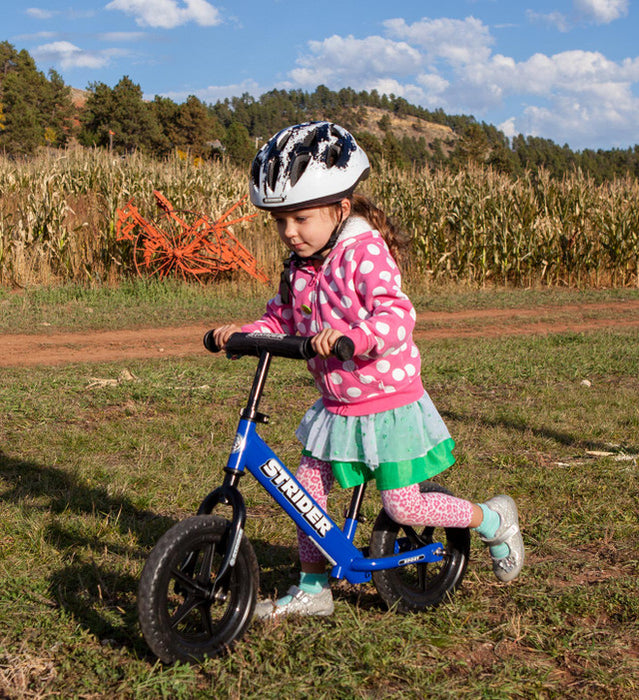 Strider Splash Kids Bike Helmet - White with Black Splash on child riding outside in grass